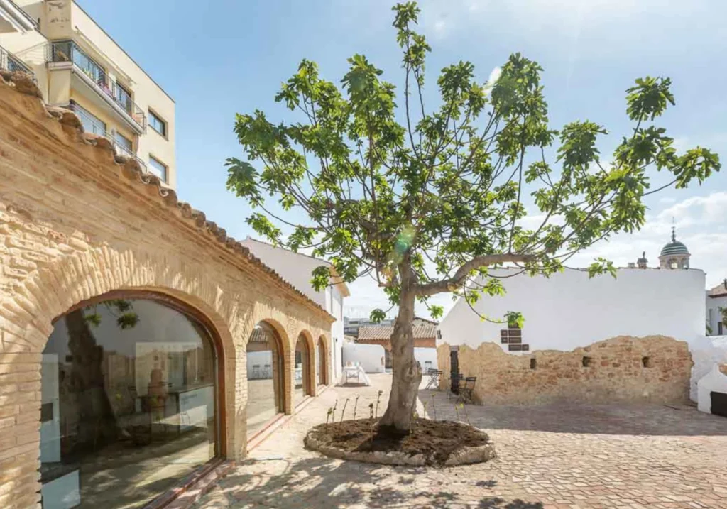 Interior courtyard of a heritage building with brick arches and a tree at its centre