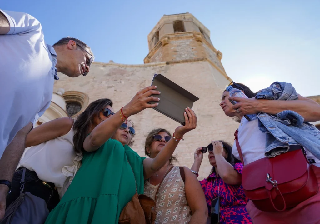 Group of people consulting a tablet during a guided tour of a historic building in Sitges