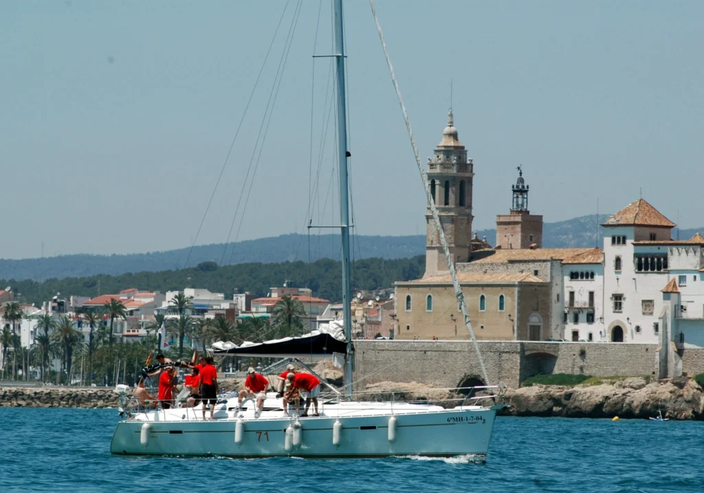 Sailing boat in front of Sant Bartomeu church and Cau Ferrat Museum in Sitges