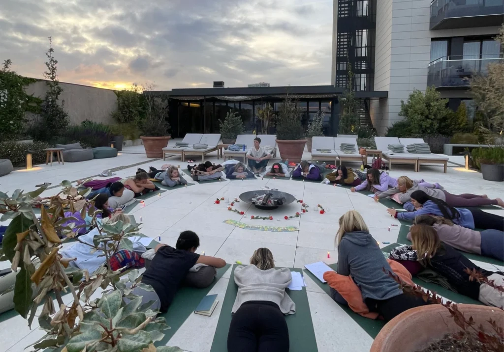 Group relaxation and meditation session on a Sitges hotel rooftop terrace at dusk