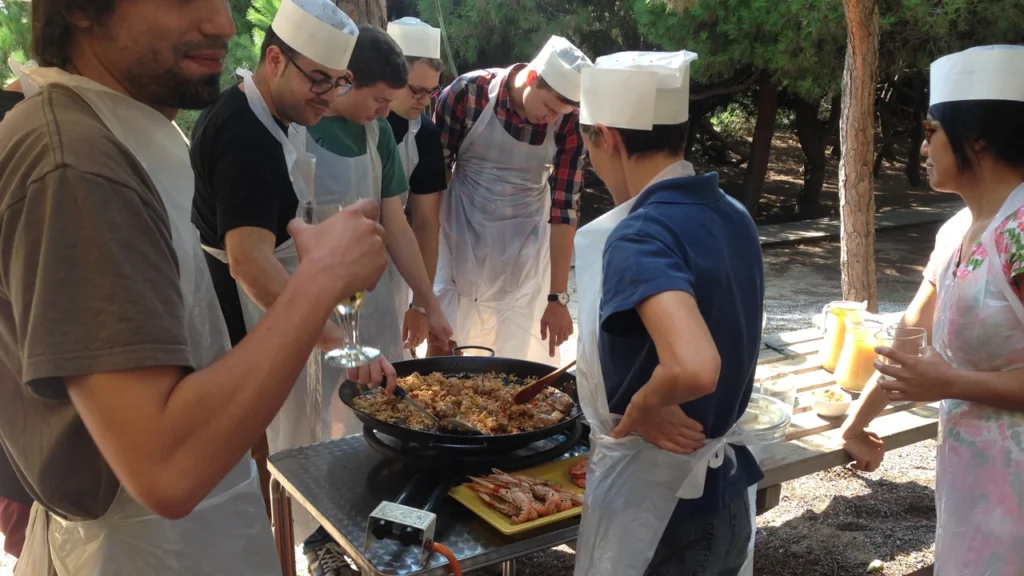 Group wearing chef hats preparing paella outdoors as a team building activity