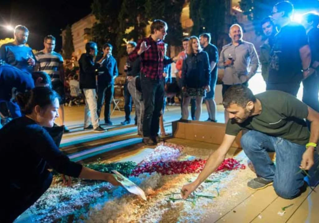 Participants creating a flower carpet at night during a team building activity in Sitges