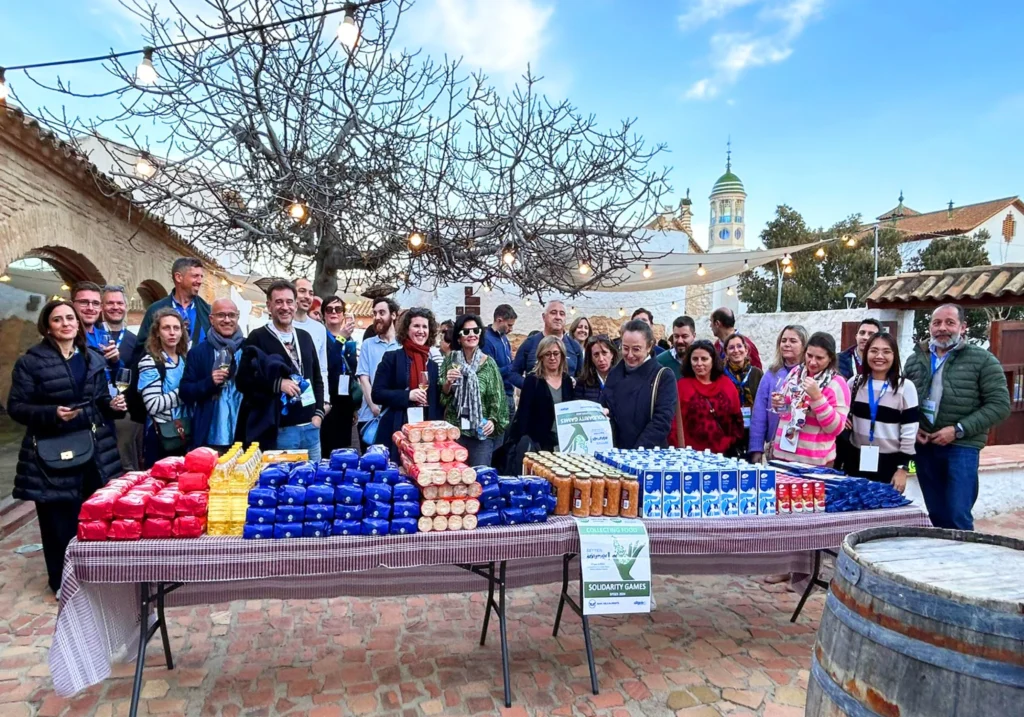 Large group posing by a product table during a solidarity team building activity in Sitges