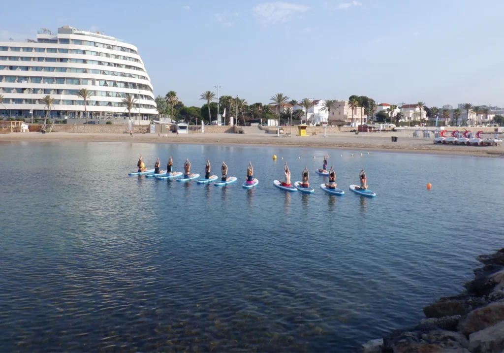 Group practising yoga on paddleboards in the sea off the Sitges coast