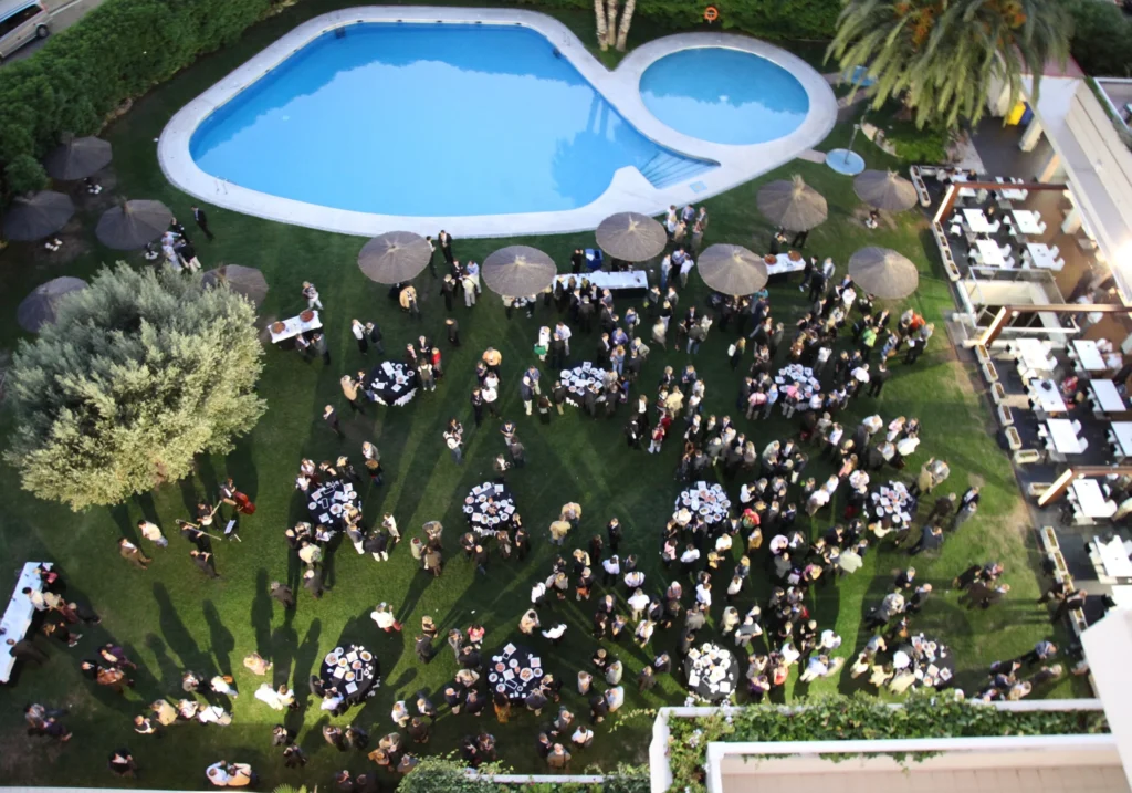 Aerial view of a networking reception in a hotel garden with pool in Sitges
