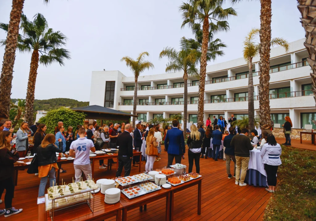 Outdoor corporate reception on a Sitges hotel terrace with palm trees and buffet