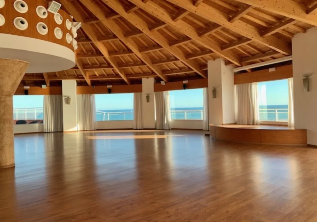 Empty multipurpose hall with a wooden ceiling and large windows overlooking the sea