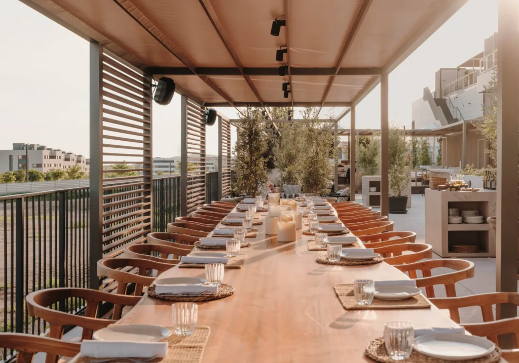 Terrace with a long table elegantly set for a private dinner at sunset