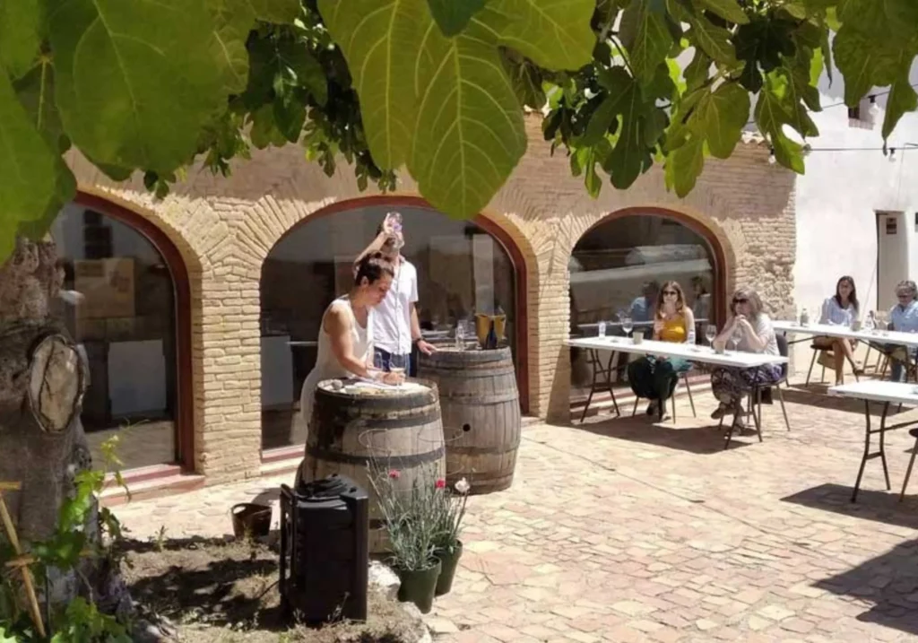 Wine tasting activity in the outdoor courtyard of a winery with wooden barrels