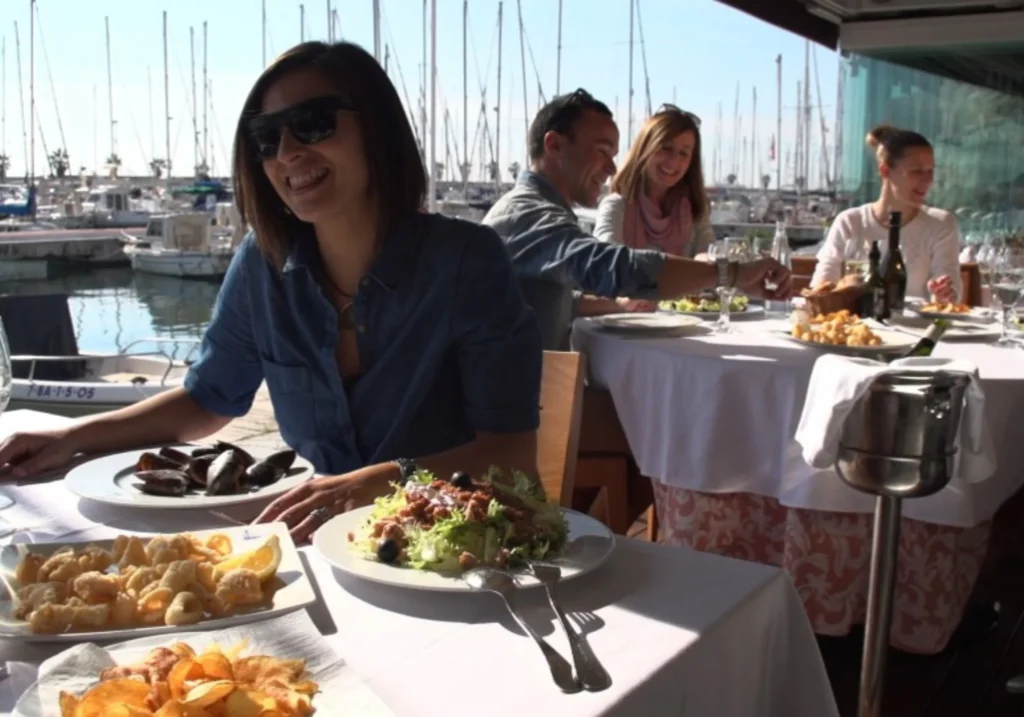 People enjoying lunch at a Sitges marina restaurant with sea views