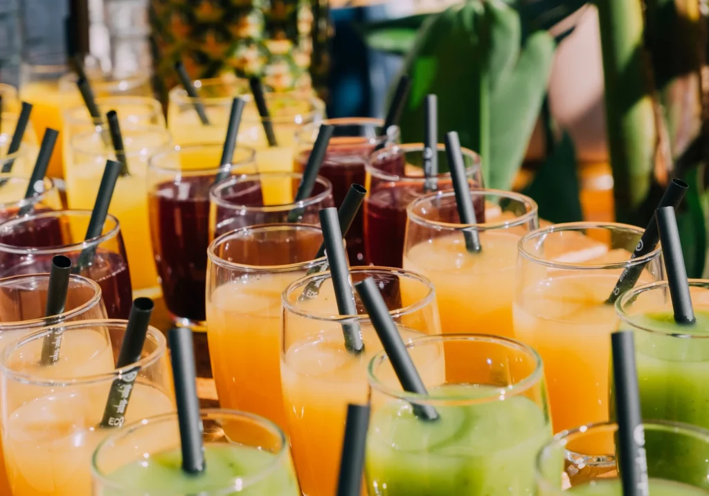 Colourful cocktails and juices served with straws in glass cups