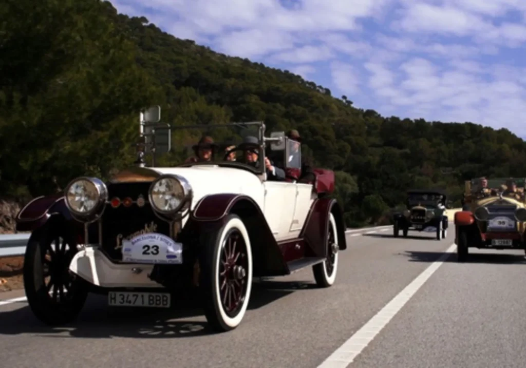 Vintage cars competing in a classic car rally on a mountain road near Sitges